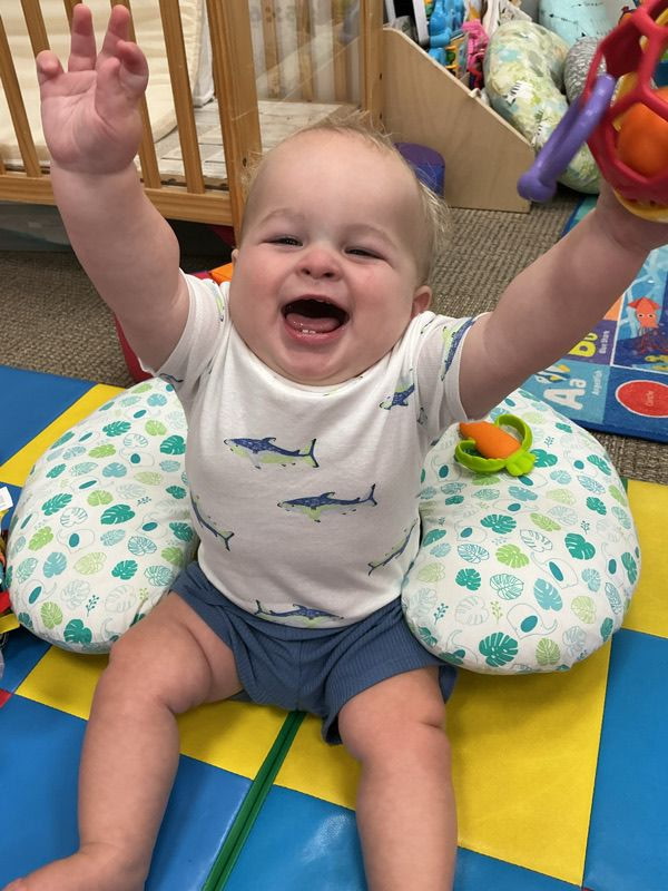 A baby smiling during classroom play at Lily Pads