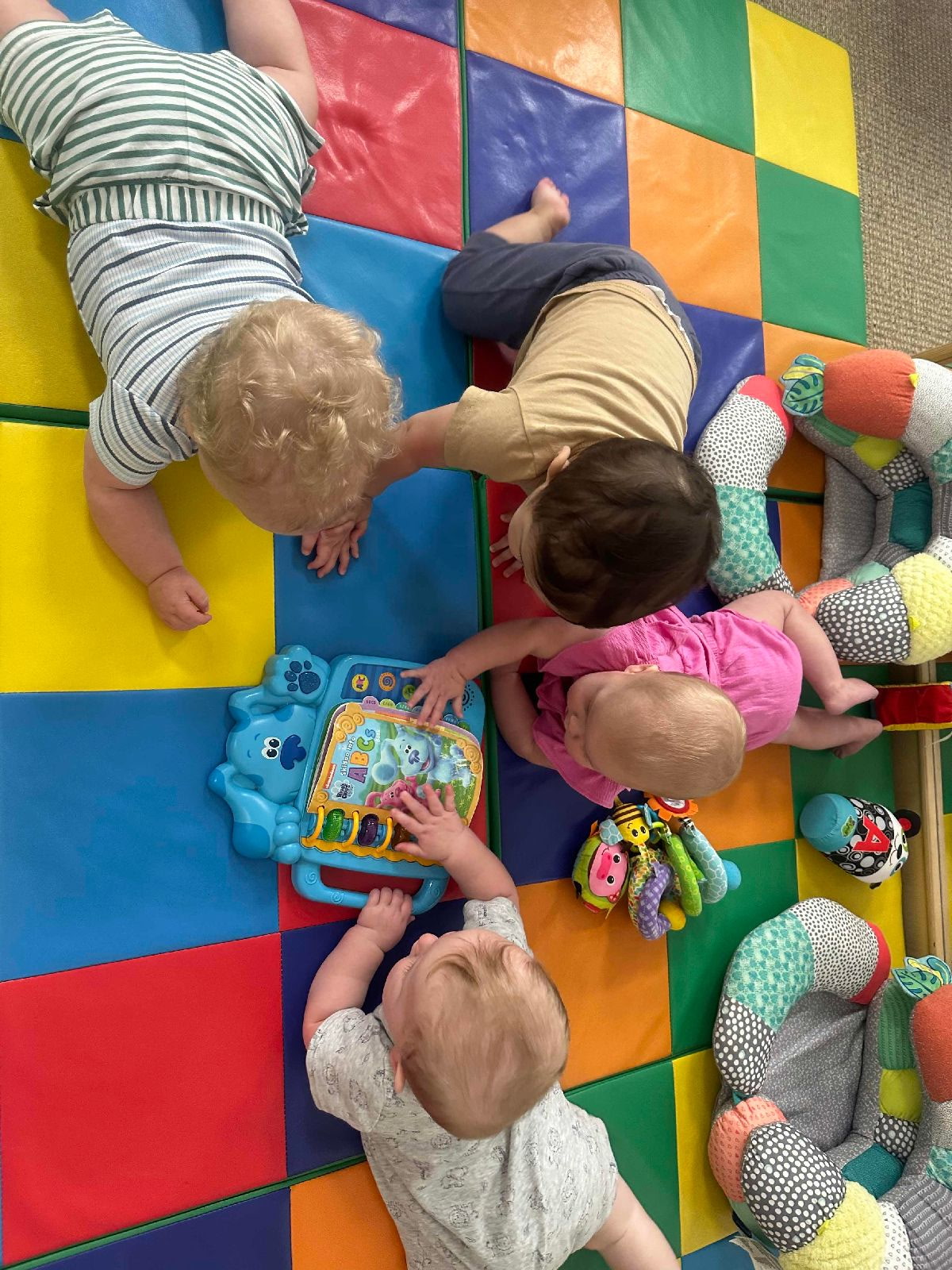 Children exploring toys together on the classroom rug